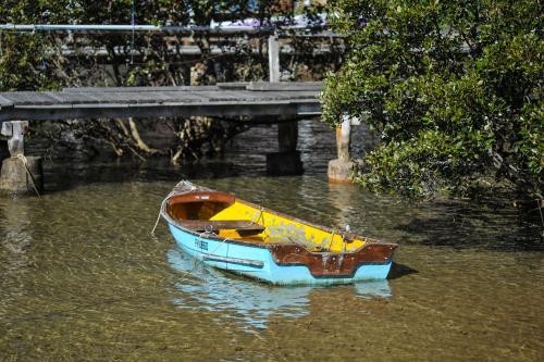 Blue boat in shallow water with wooden bridge - Australian Stock Image