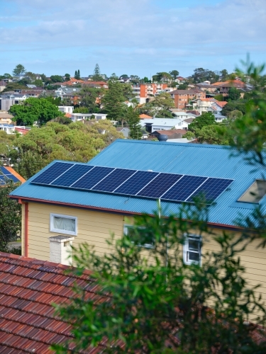 Blue coloured roof with solar panels and a view with houses