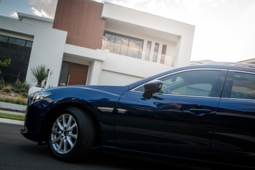 Blue station wagon on suburban street with luxury homes - Australian Stock Image