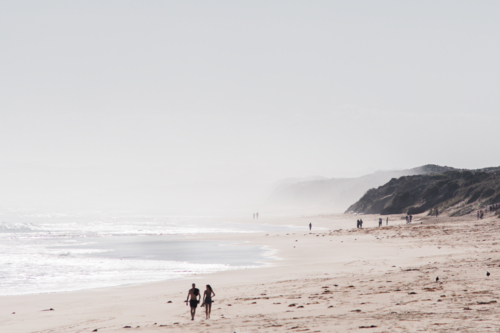 blurred couple walking on hazy beach on summers day - Australian Stock Image