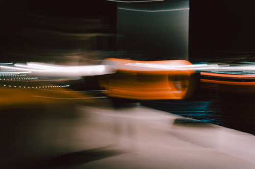 Blurred orange motion streaks glowing across dimly lit urban nightscape - Australian Stock Image
