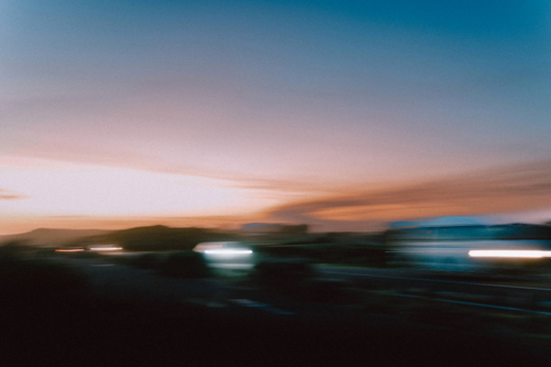 Blurred sunset road with moving cars flashing lights - Australian Stock Image