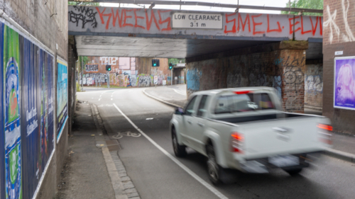 Blurred vehicle driving under a blurry railway bridge covered in graffiti - Australian Stock Image