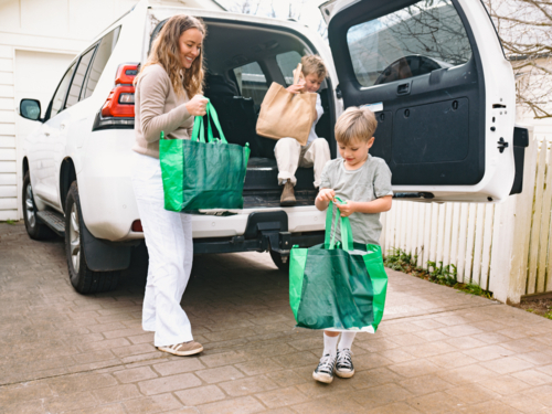 blurred Young boys helping mum unload grocery bags from car boot - Australian Stock Image