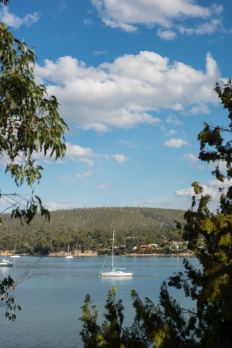 Boat in calm water surrounded by trees and hills - Australian Stock Image