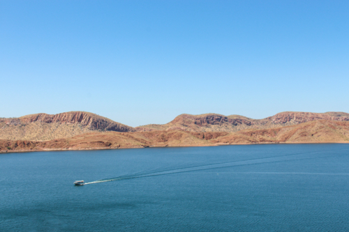 Boat sailing across lake with mountain views - Australian Stock Image
