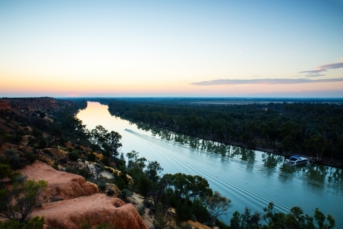 boat travelling down river at sunset - Australian Stock Image