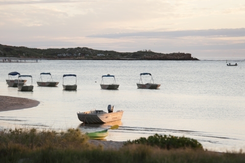 Boats and kayak in bay at sunset - Australian Stock Image