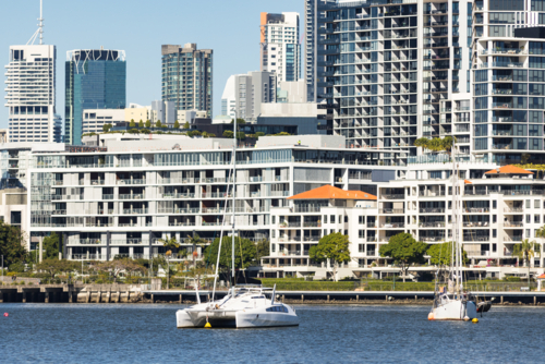 Boats on the Brisbane River with riverfront apartment blocks lining the river in Newstead - Australian Stock Image