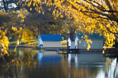 Boatsheds on a lake in Autumn - Australian Stock Image