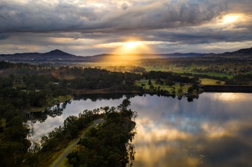 Body of calm water mirrors the cloudy sky in sunset landscape - Australian Stock Image