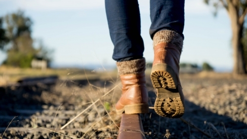 Booted feet walking away on railway tracks - Australian Stock Image