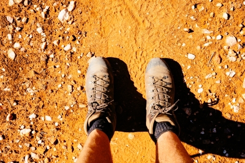 Boots and legs on a red earth trail in Central Australia. - Australian Stock Image