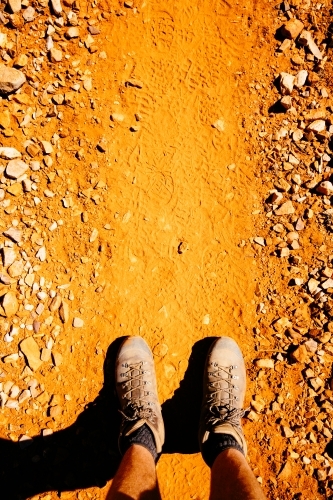 Boots and legs on a red earth trail in Central Australia. - Australian Stock Image