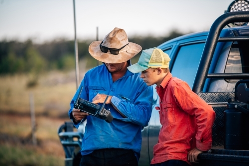 Boss showing worker remote control - Australian Stock Image