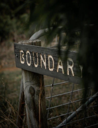 BOUNDARY -  Worn Out Wooden Sign on the edge of a Moody Forest