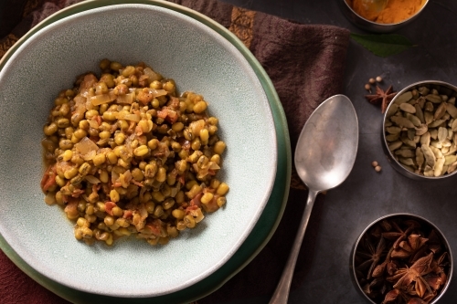 Bowl of Dahl Curry and ingredients around on dark background - Australian Stock Image
