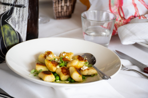 Bowl of Gnocchi with serving spoon on a dinner table - Australian Stock Image