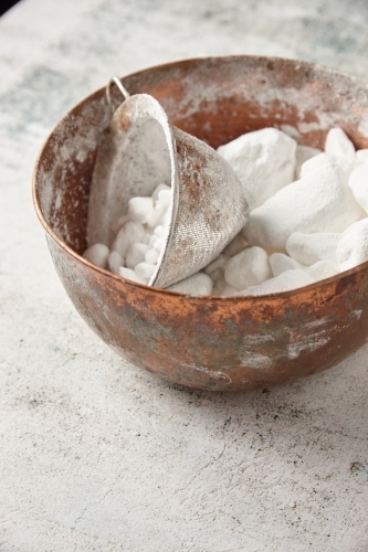 Bowl of lumpy icing sugar with sieve - Australian Stock Image
