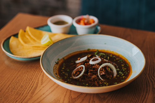 bowl of Mexican Stew birria Served With Tortillas and Garnishes - Australian Stock Image