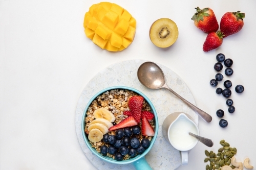 Bowl of muesli with tropical fruit on white table