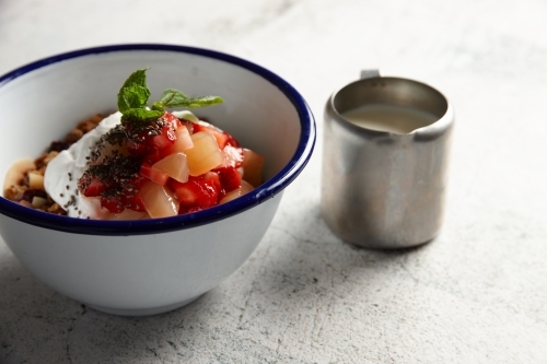 Bowl of muesli with yoghurt and fruit with jug of milk on the side - Australian Stock Image