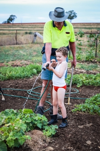 Boy and man on farm watering plants