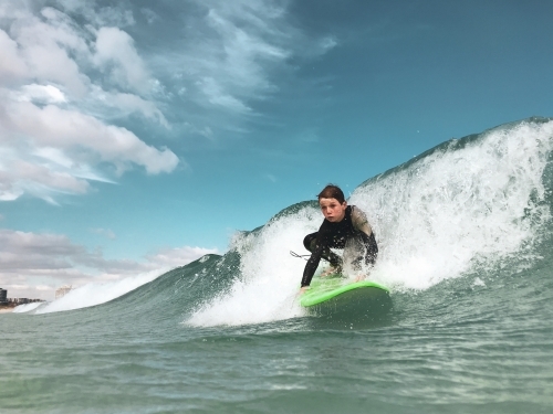 Boy catching wave on foam surfboard taken in water