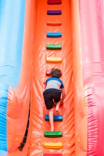 Boy climbing up ladder of blow up slide at local show - Australian Stock Image