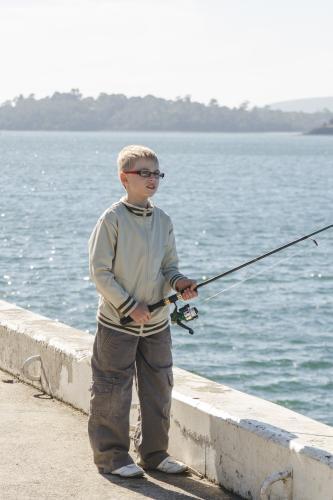 Boy fishing off wharf on a sunny day