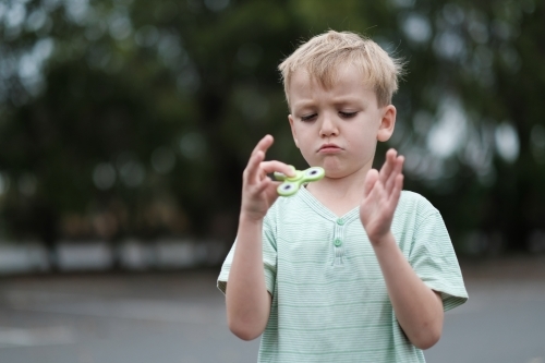 Boy frowning playing with fidget spinner toy