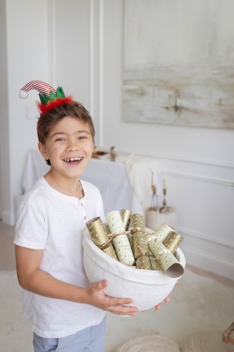 Boy holding bowl of Christmas crackers - Australian Stock Image