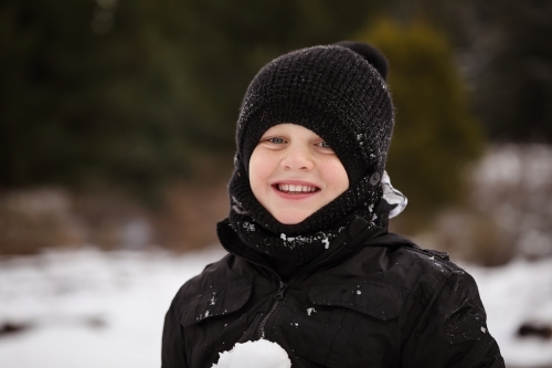 Boy in the snow with snow ball having snowball fight - Australian Stock Image