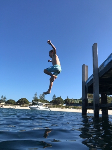 Boy jumping off jetty into river