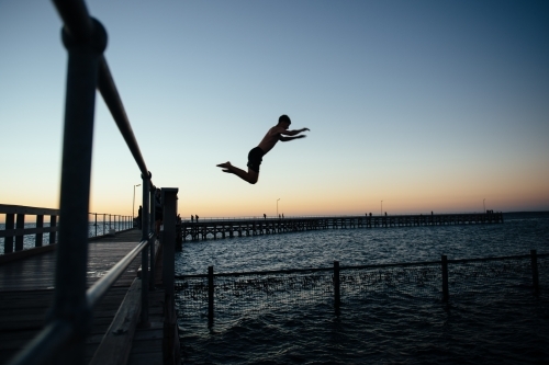 Boy leaping from pier - Australian Stock Image