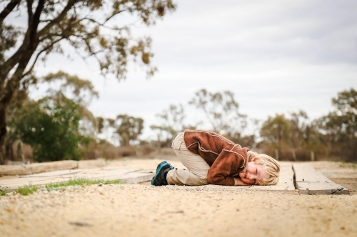 boy lying on bridge on rural country road - Australian Stock Image