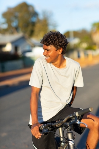 boy on bike looking away and smiling - Australian Stock Image