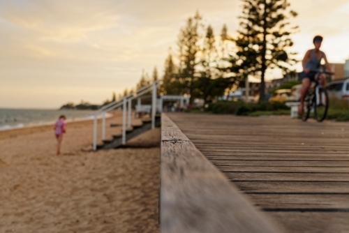 Boy on pushbike riding along coastal boardwalk - Australian Stock Image
