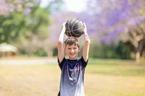 Boy playing outside with Jacaranda flowers - Australian Stock Image