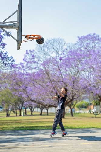 Boy playing outside with Jacaranda flowers - Australian Stock Image