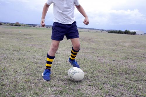 Boy playing with a football on the ground - Australian Stock Image
