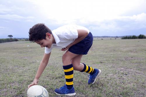 Boy playing with football on a field - Australian Stock Image