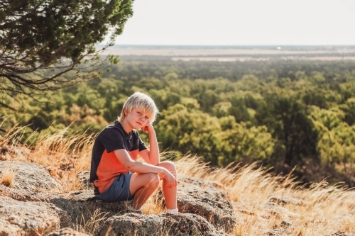 Boy resting on rock during a hike in the Australian bush - Australian Stock Image