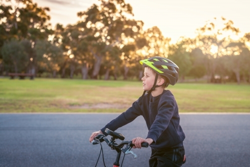 Boy riding his bicycle at sunset at Adelaide Park Lands - Australian Stock Image