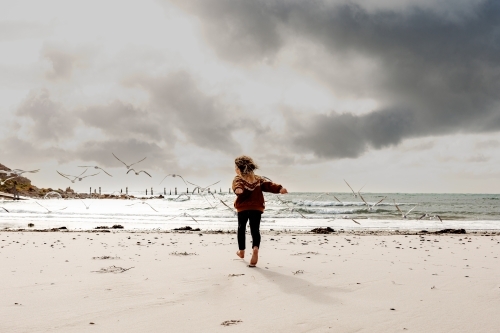 Boy running on the beach chasing birds
