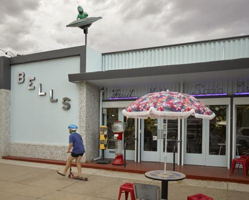 Boy scootering past Bells Milk Bar on an overcast day - Australian Stock Image