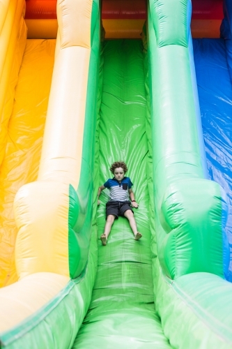 Boy sliding down blow up slide at local show - Australian Stock Image