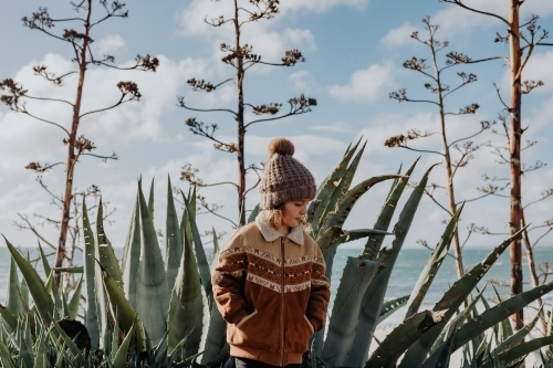 Boy standing in front of cactus' with the ocean behind - Australian Stock Image