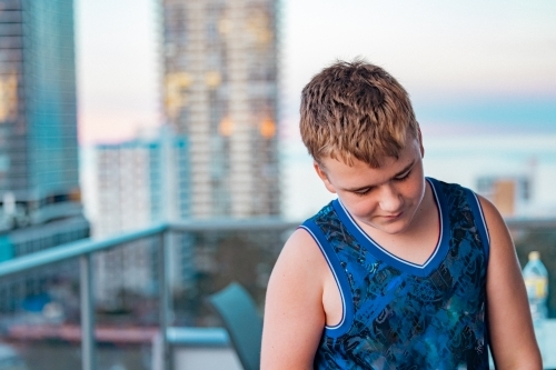 Boy standing on the balcony of a high rise apartment in Surfers Paradise, Queensland Australia - Australian Stock Image