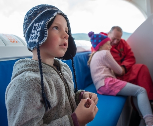 Boy travelling on a boat in cold weather - Australian Stock Image
